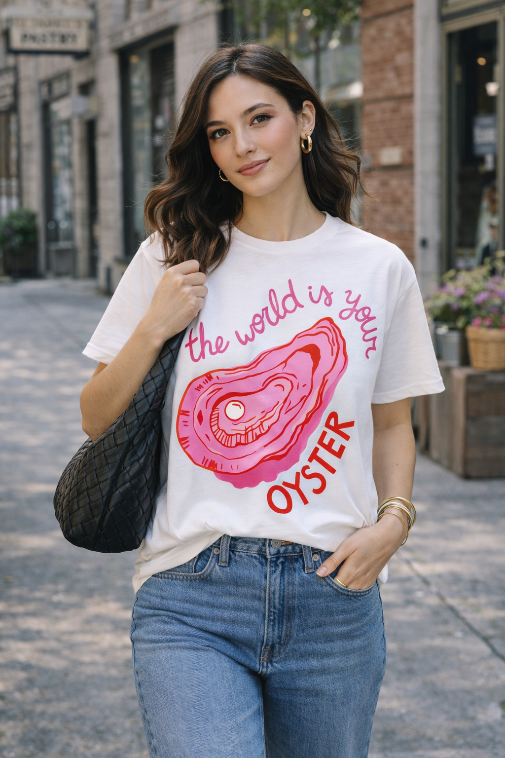Woman wearing a t-shirt with an oyster graphic and text on a city street.