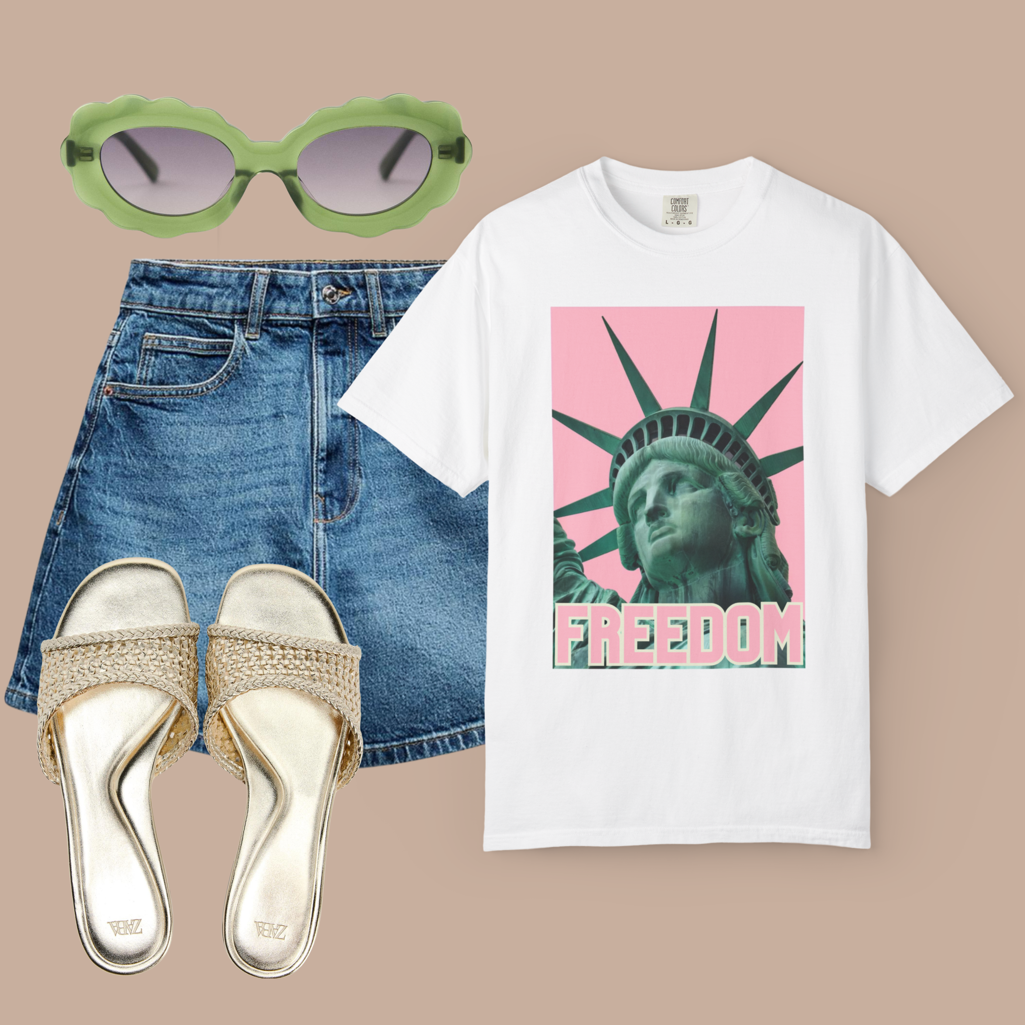 White Comfort Colors tee with green Statue of Liberty and pink background, styled with a denim skirt, gold sandals, and green sunglasses.


